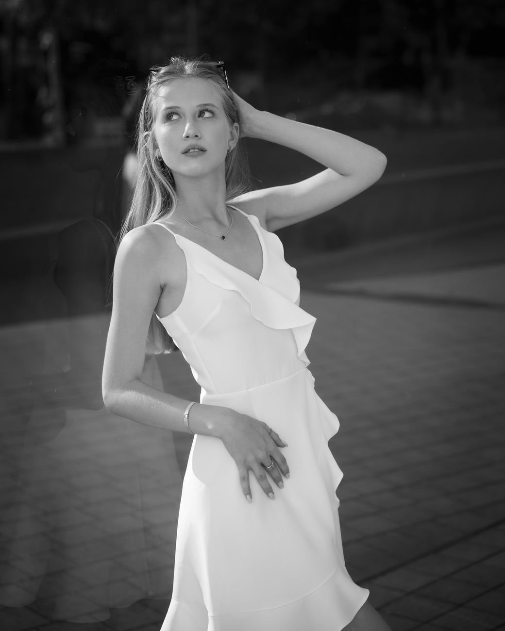 Black and white portrait of an elegant woman in a white dress posed outdoors